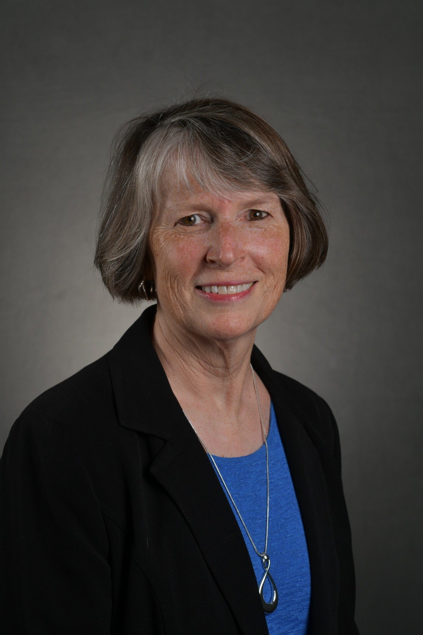 Raw studio headshot with plain gray background before professional brand styling